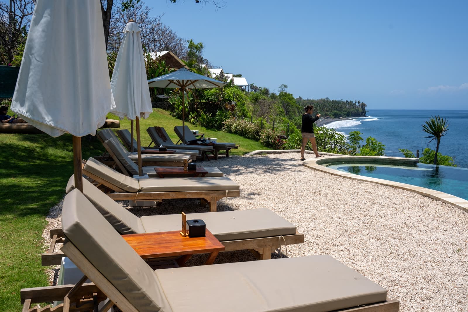 Hồ bơi resort ven biển với ghế nằm dưới hàng dừa